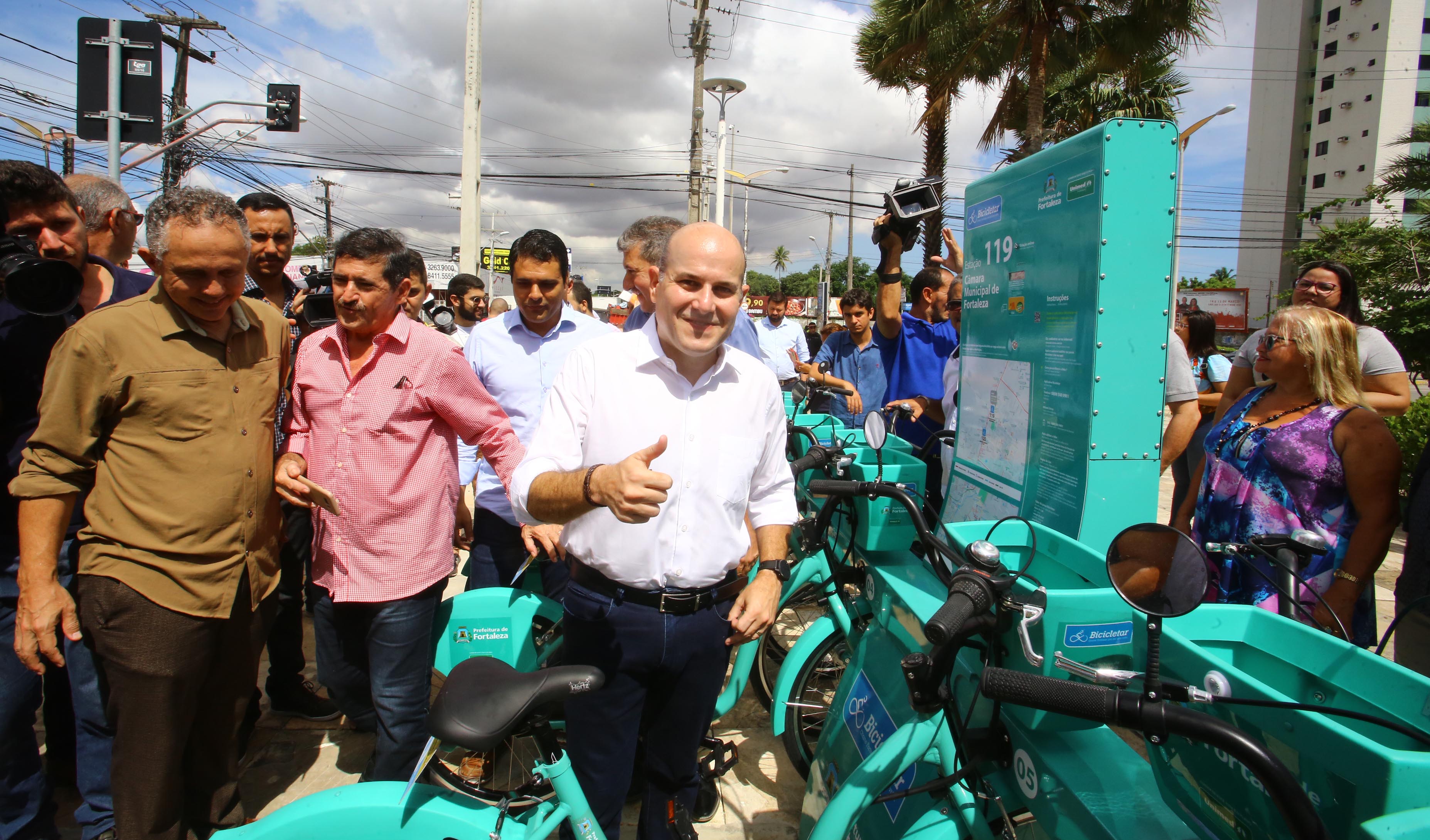 prefeito fazendo sinal de positivo e sorrindo para foto ao lado de pessoas e bicicletas